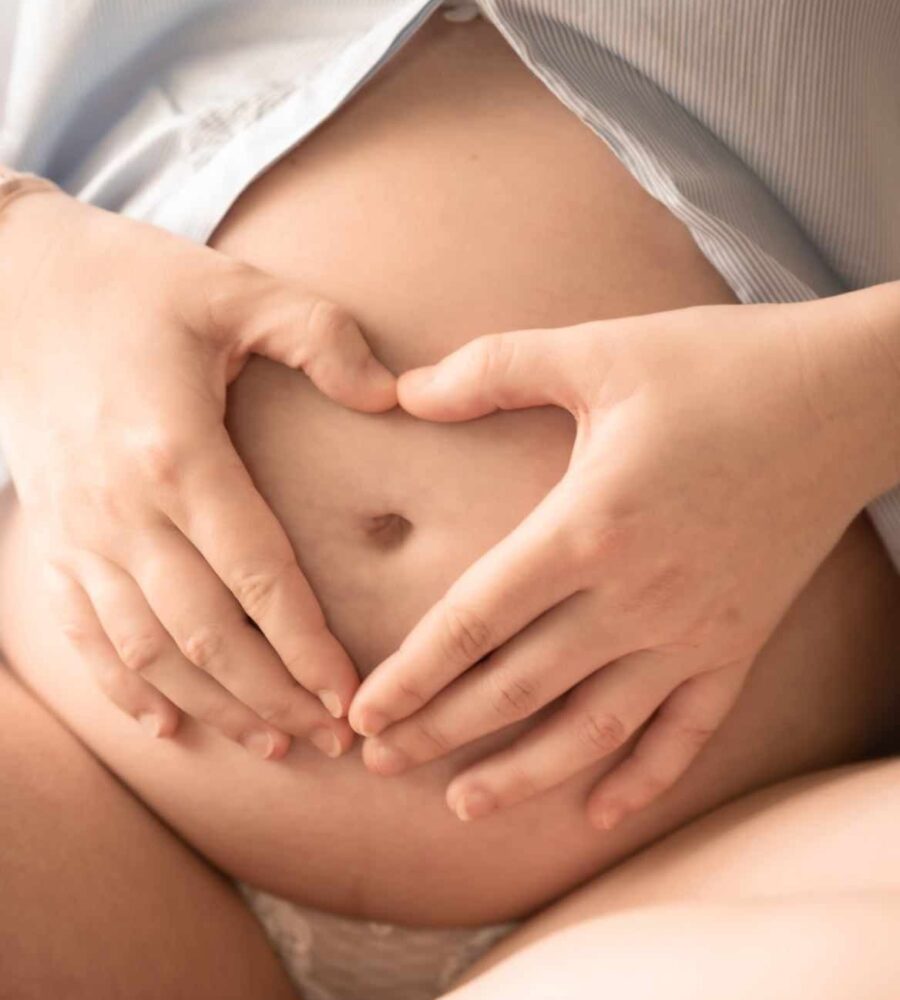 mains qui forment un cœur sur le ventre d'une femme enceinte. ventre de femme enceinte. chemise ouverte sur le ventre