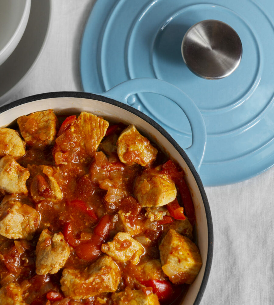 cocotte bleu dans lequel on voit un petit plat. De la viande blanche, de la tomate, de la sauce.